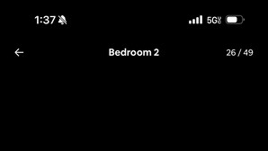 A black dresser with multiple drawers and knobs, placed against a light blue wall in a bedroom.