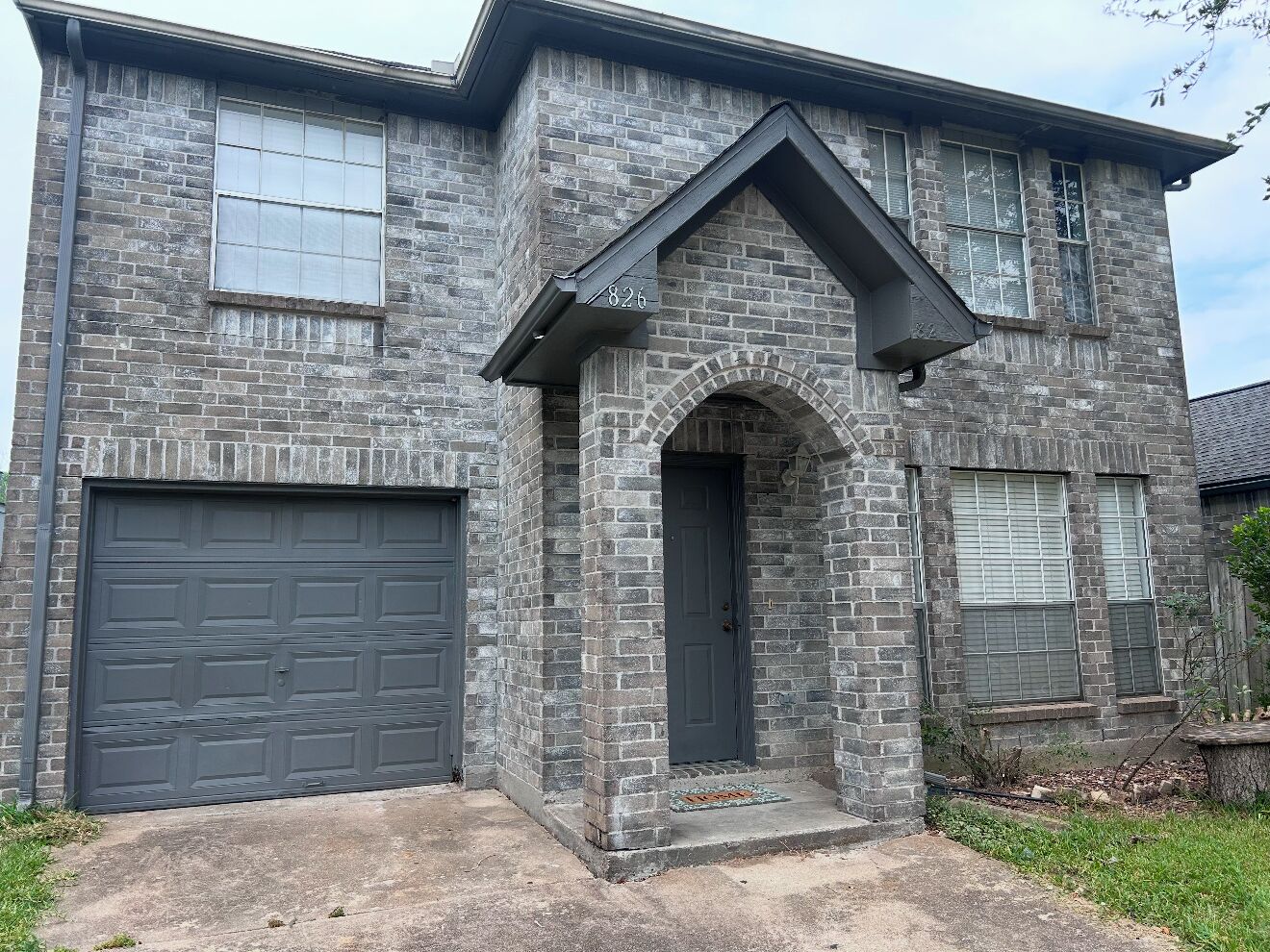 A two-story house with a stone facade, a garage, and a front door.