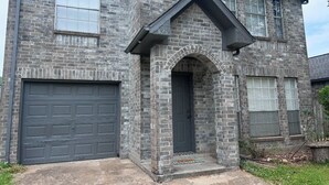 A two-story house with a stone facade, a garage, and a front door.