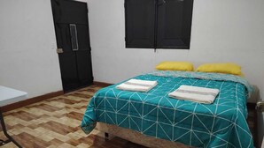 A bedroom with a bed, two yellow pillows, a teal and white patterned bedspread, and a wooden parquet floor. - Chalet & hotel with private Sw pool for 6 to 9  people Puerto San José Guatemala (Puerto San José)