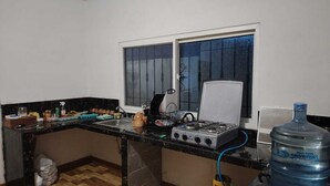 A kitchen with a gas stove, a water dispenser, and a window with bars. - Chalet & hotel with private Sw pool for 6 to 9  people Puerto San José Guatemala (Puerto San José)