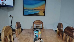 A large wooden dining table with six chairs, a television on the wall, and a painting above the table. - Chalet & hotel with private Sw pool for 6 to 9  people Puerto San José Guatemala (Puerto San José)
