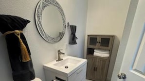 A bathroom with a toilet, sink, mirror, and cabinet.