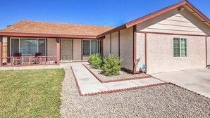 A single-story house with a covered patio, a small garden, and a gravel driveway.