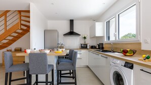 A modern kitchen with a dining area, a washing machine, and a staircase. - Le Pré Tarin by Interhome (La Bernerie-en Retz)