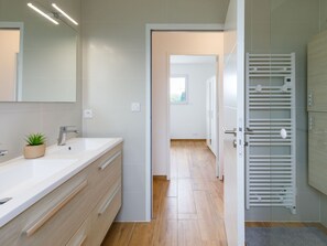 A modern bathroom with a large mirror, a sink, and a towel rack.