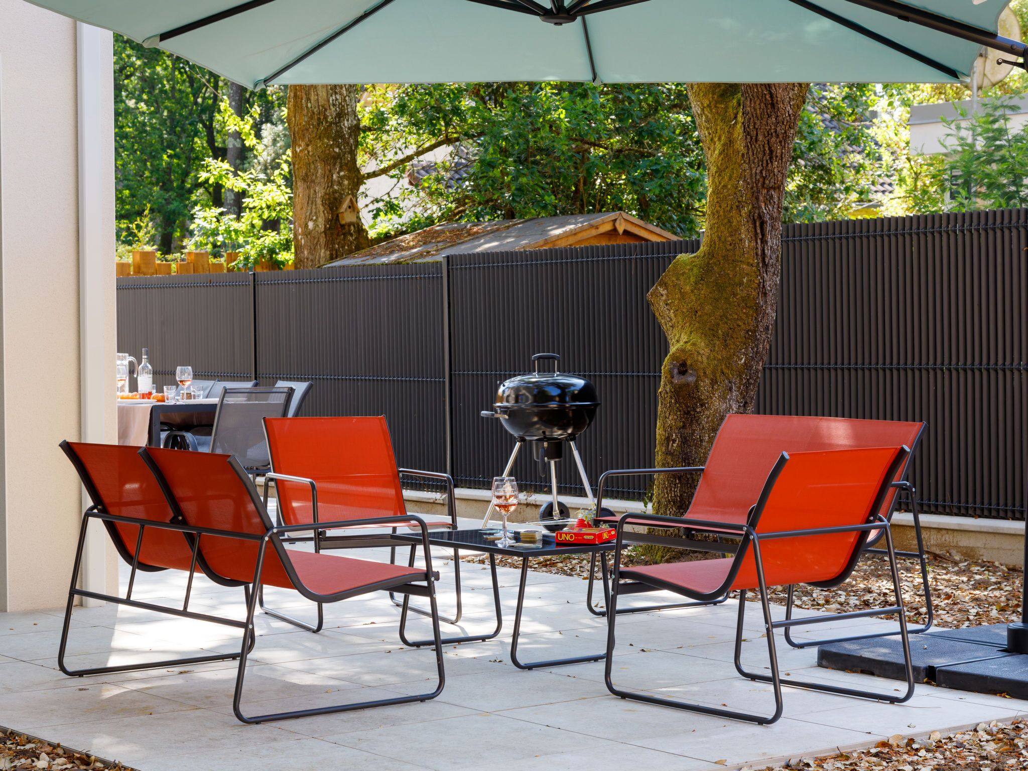 Patio esterno con tavolo, sedie e barbecue.
