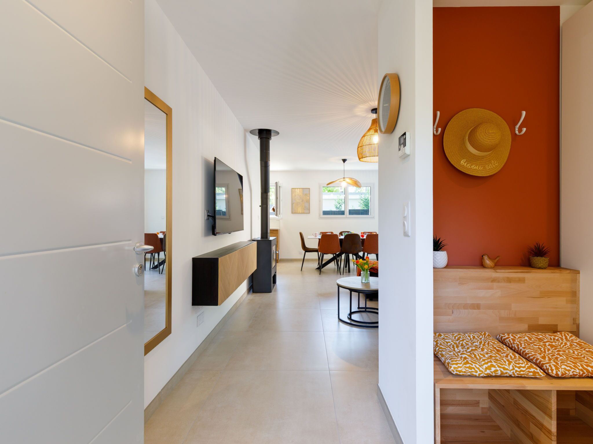 A modern living room with a fireplace, a dining area, and a kitchen visible through an open door.
