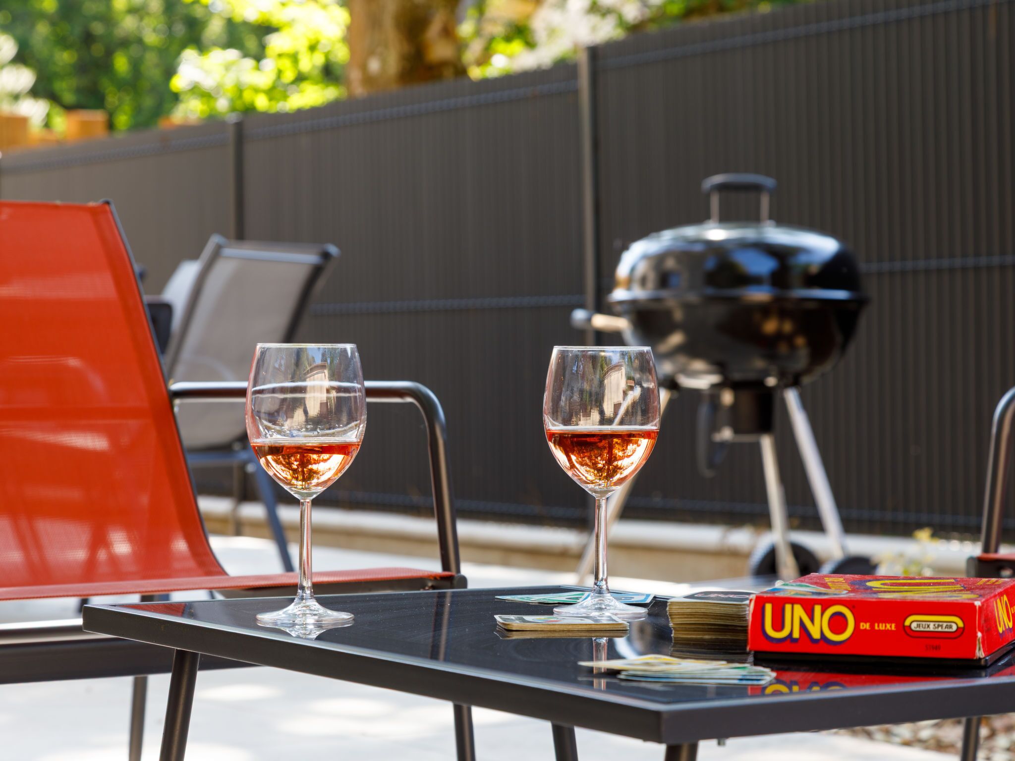 A table with two wine glasses, a grill, and a UNO game box.