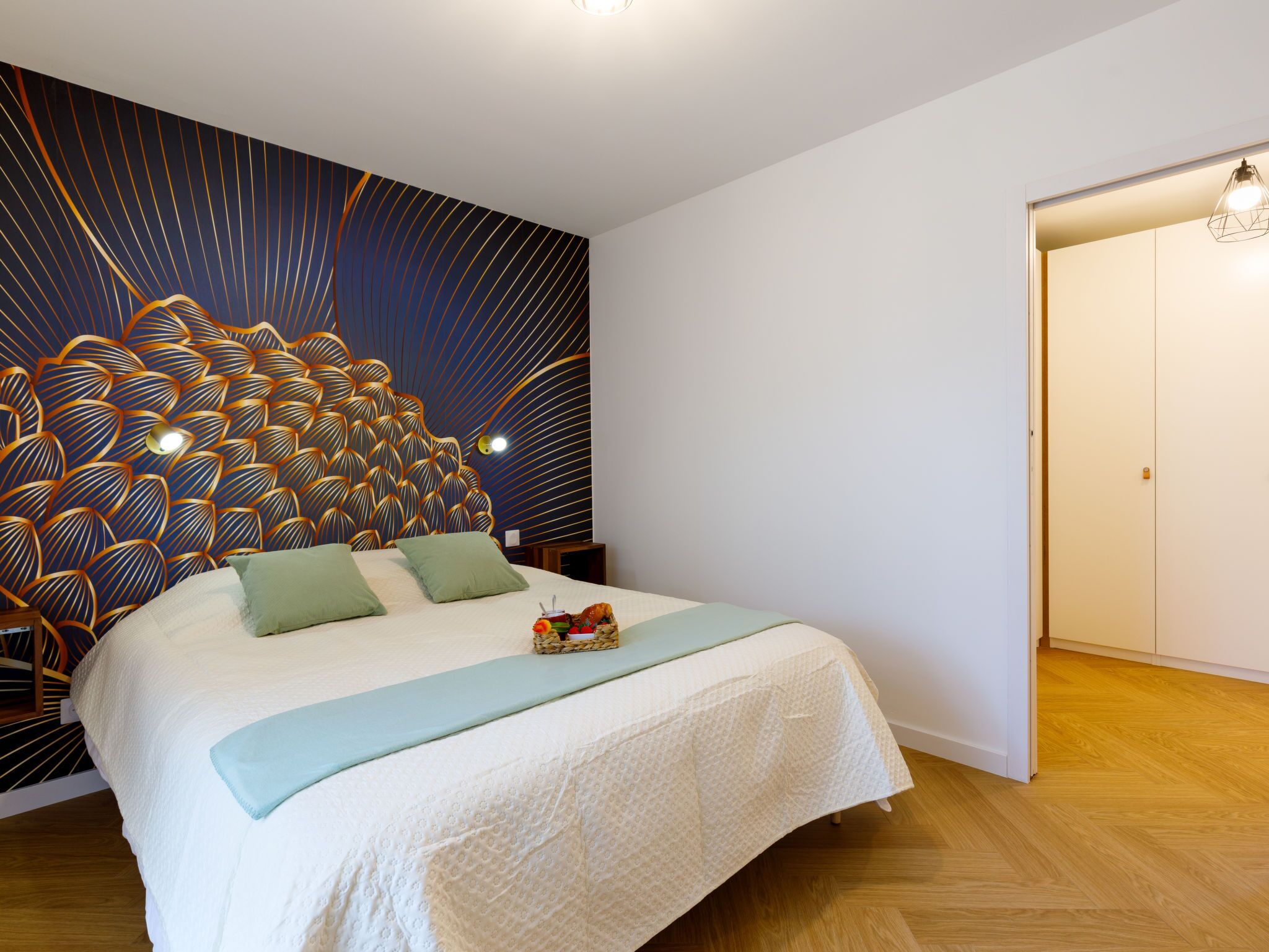 Un dormitorio con una cama grande, un cabecero decorativo y suelo de madera.