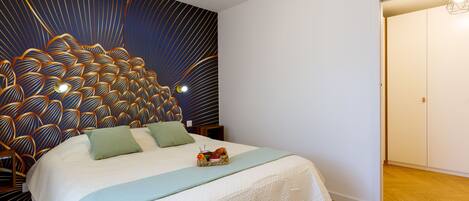 Un dormitorio con una cama grande, un cabecero decorativo y suelo de madera.