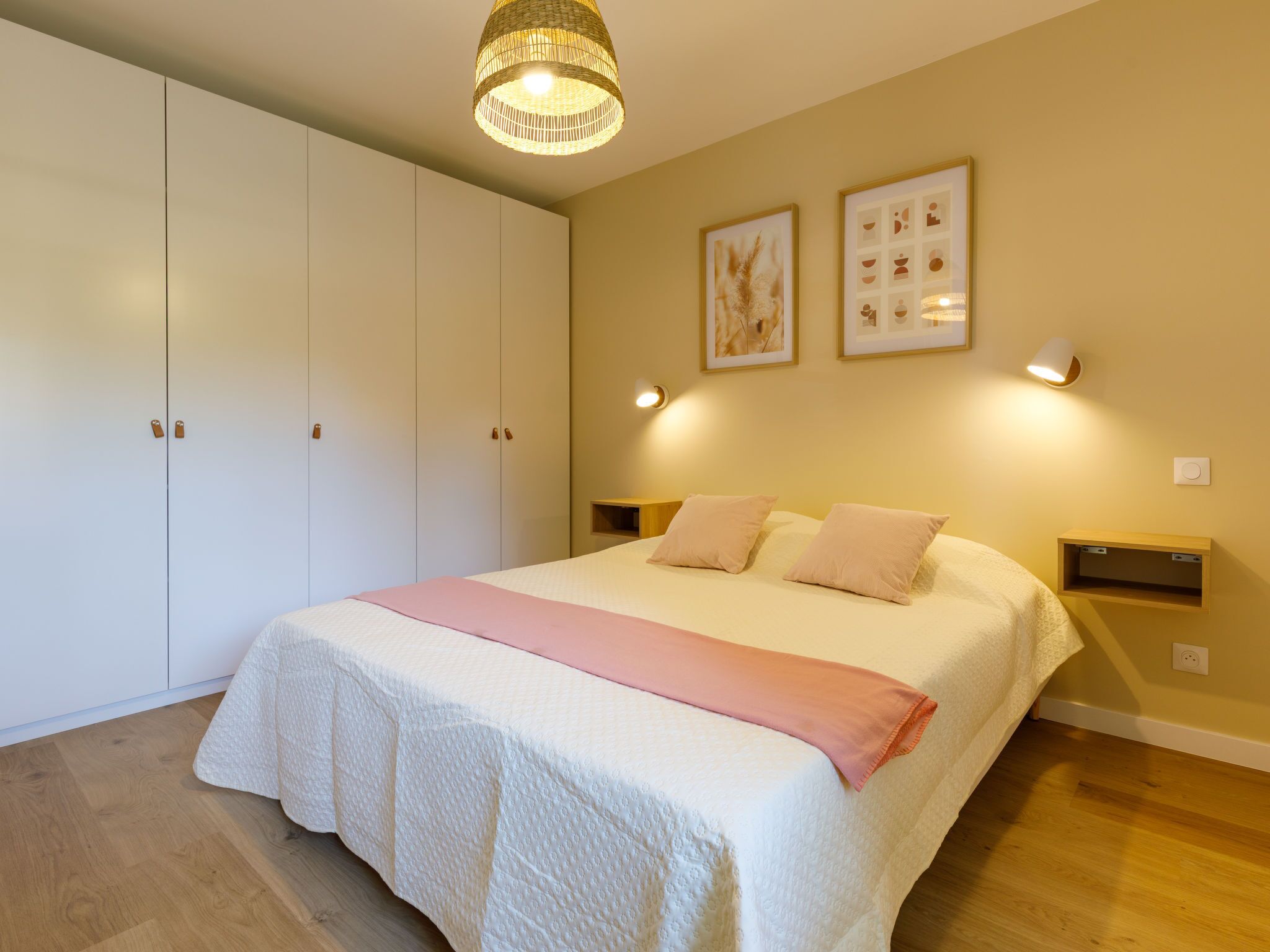 Een slaapkamer met een groot bed, een kledingkast en twee nachtkastjes aan de muur.