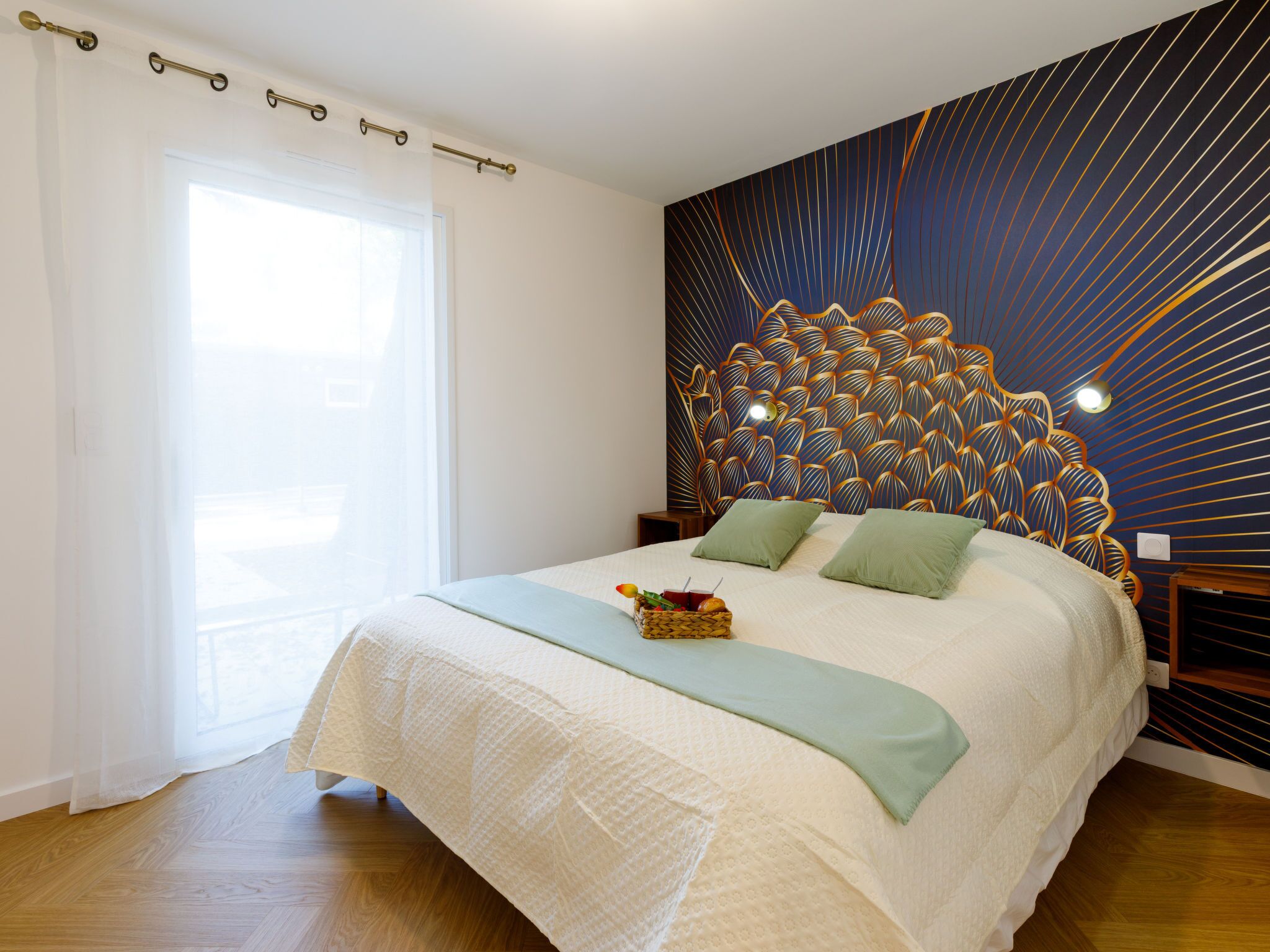 A bedroom with a large bed, a decorative headboard, a bedside table, and a window with curtains.