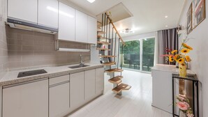 Ett modernt kök med en central köksö, en inbyggd spis och en trappa som leder upp till en balkong.