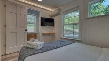 Une chambre à coucher avec un lit, une télévision, une fenêtre et une porte.