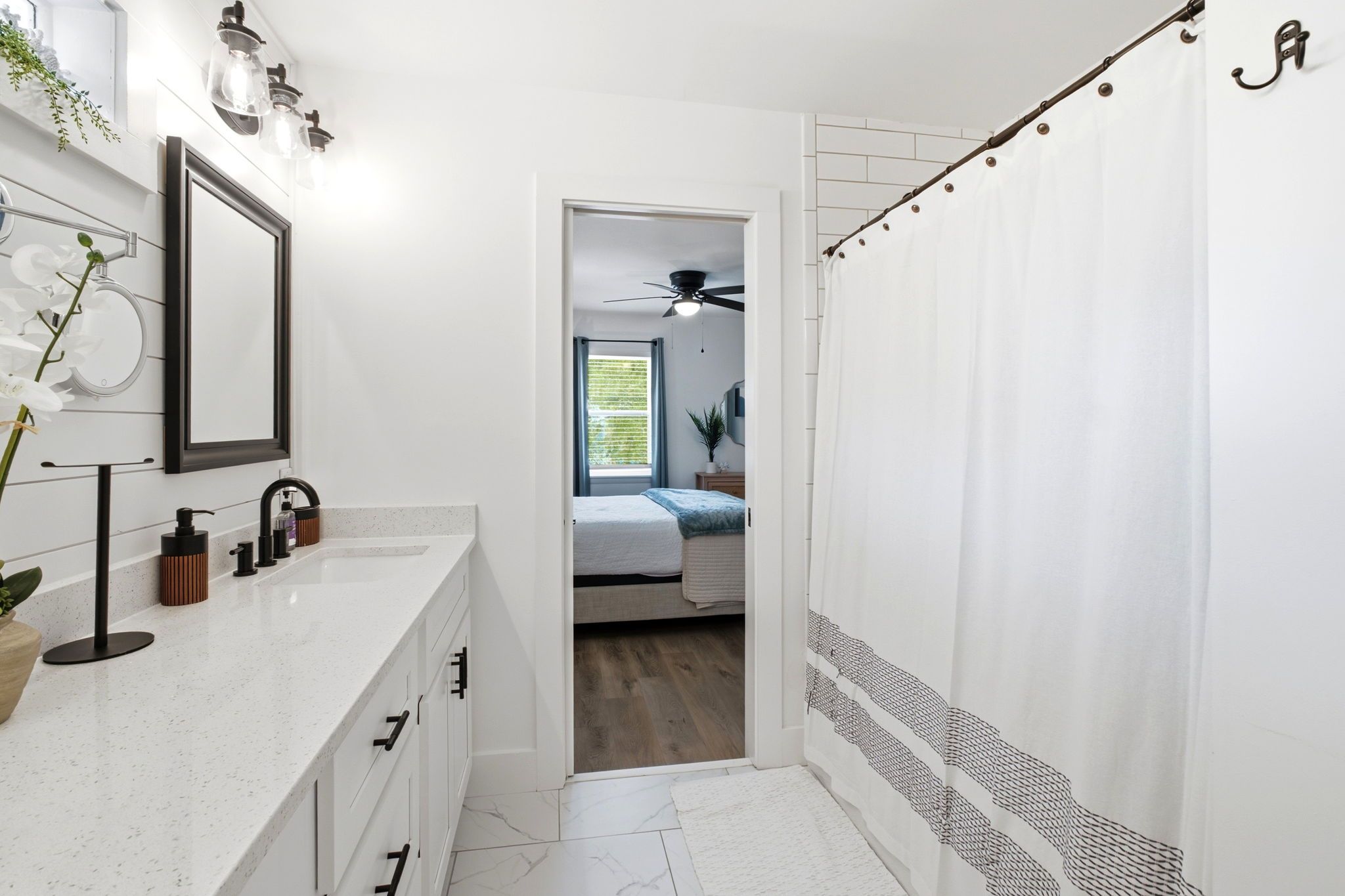 A modern bathroom with a white vanity, a mirror, and a ceiling fan.