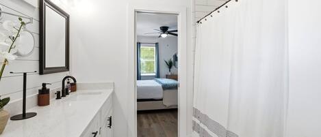 A modern bathroom with a white vanity, a mirror, and a ceiling fan.