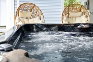 A hot tub with two wicker chairs, each with a cushion.