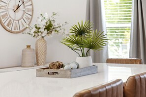 A dining table with a plant, decorative items, and a clock on the wall.