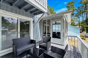 Ett takförsett utomhusområde med ett matbord och stolar, en takfläkt och utsikt över trädgården.