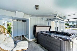Un jacuzzi en una habitación con ventilador de techo, una silla de mimbre y una puerta que da al exterior.