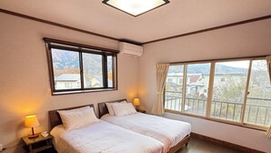 Camera d'albergo con due letti, un'ampia finestra vista e un comodino con lampada.