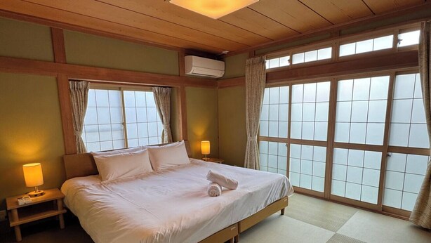 Camera d'albergo con un letto grande, due comodini con lampade, una finestra vista e un ventilatore a soffitto.