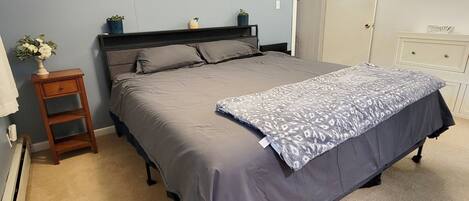 Un dormitorio con cama, mesita de noche, cómoda y puerta.