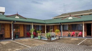 A courtyard with brick flooring, potted plants, and outdoor seating. - Arabella Motor Inn (Tweed Heads South)