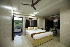 A hotel room with a bed, a ceiling fan, a window with curtains, and a balcony. - Hotel Park Gardenia (Nagpur)
