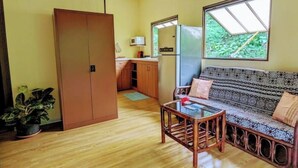 A compact living space with a sofa, a small table, a kitchenette, and a wardrobe.