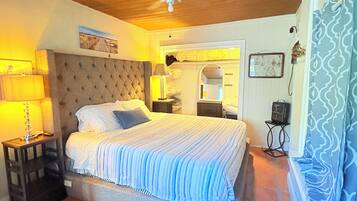 Ein Schlafzimmer mit Bett, Nachttischen, Deckenventilator und Fliesenboden.