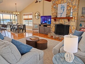 A spacious living room with a stone fireplace, a dining area with a view, and a television displaying streaming services.