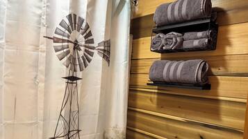 Une salle de bain décorée d’une fresque représentant un moulin à vent, avec des serviettes sur un porte-serviettes et une petite plante en pot.