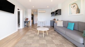 Un salon moderne avec un canapé, une table basse ronde et un coin repas comprenant une table et des chaises.