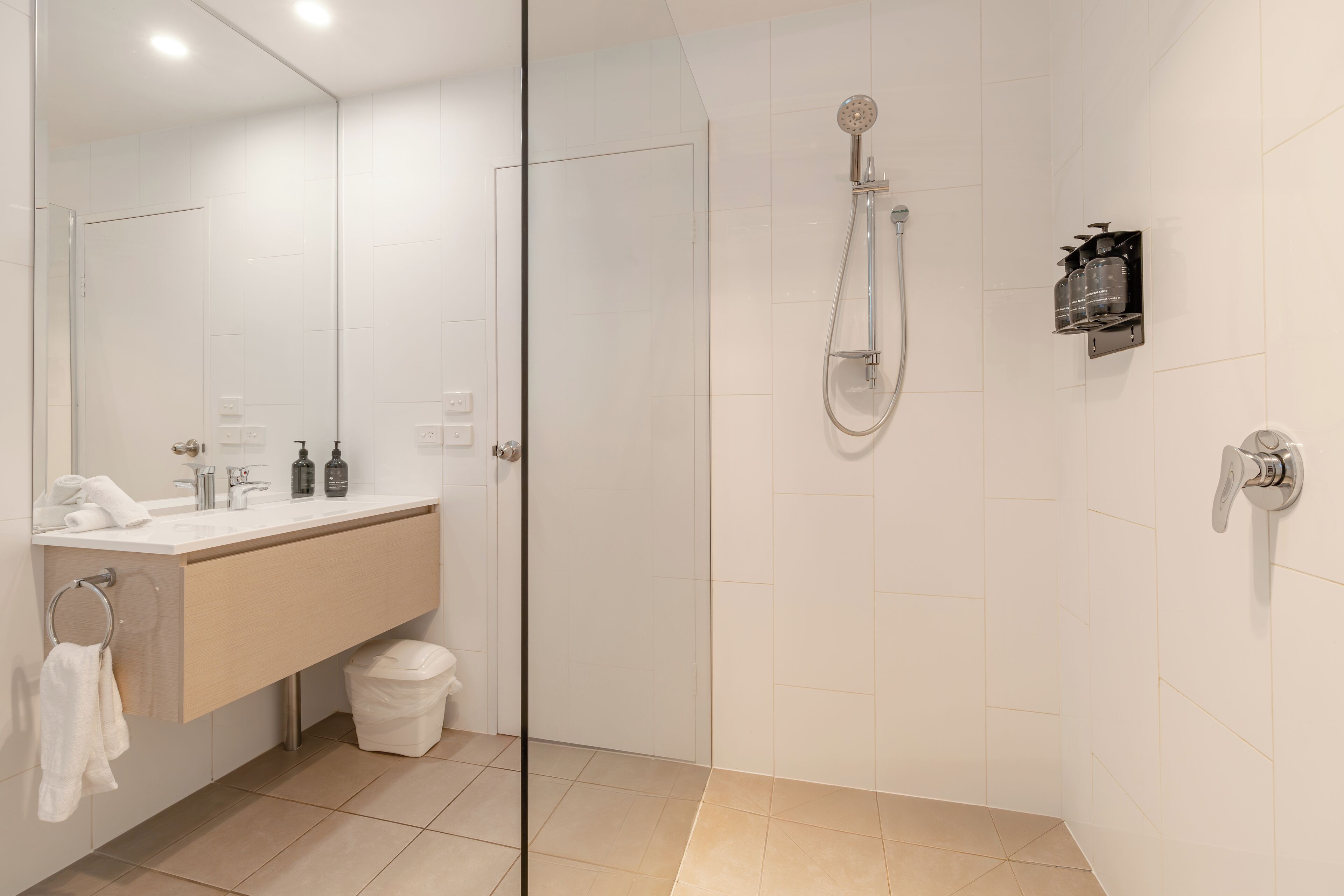 A modern bathroom with a glass shower enclosure, a vanity with a sink, and a mirror.