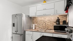 Eine moderne Küche mit einem Edelstahl-Kühlschrank, einer Mikrowelle, einem Spülbecken und einer Kaffeemaschine.