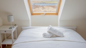 A bedroom with a skylight, a bed, a nightstand, and a lamp. - Vacation home Solace by Interhome (North Skye)