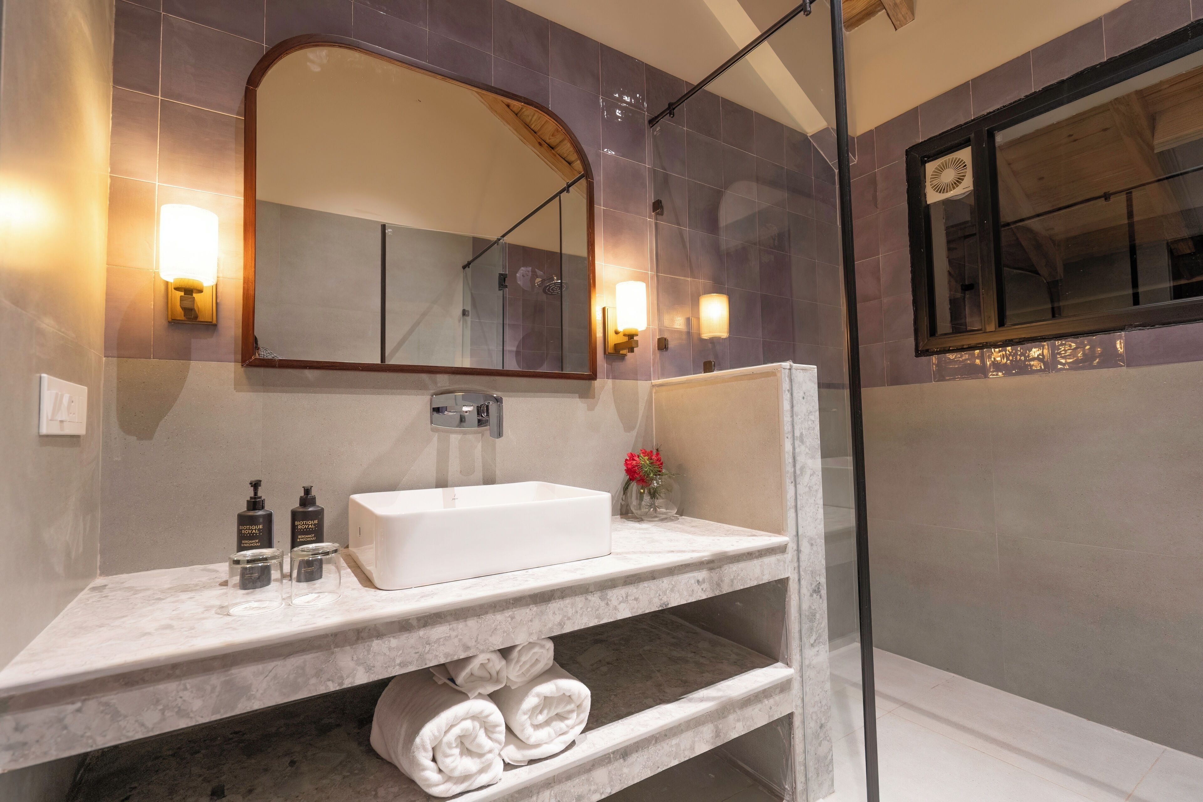 A modern bathroom with a marble sink, a large mirror, and two wall-mounted lights.