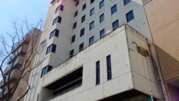 Un edificio de varios pisos con fachada plana, varias ventanas y un escaparate visible en la planta baja.