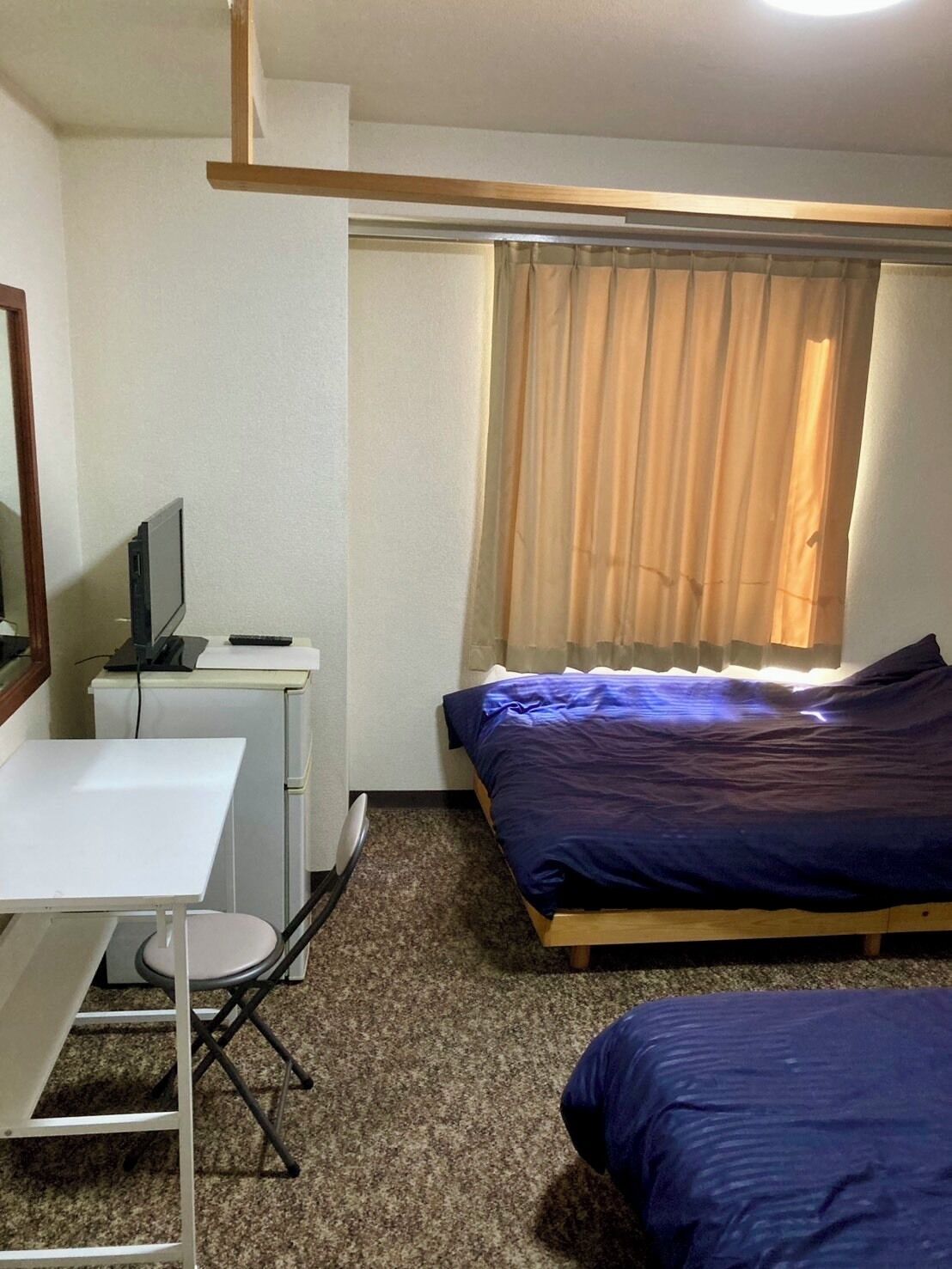 Una habitación pequeña y sencilla con una cama, un escritorio y una silla.