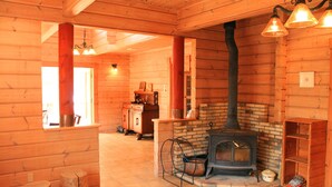 Interior d'una cabana de fusta amb una llar de foc, parets de fusta i una zona d'seients acollidora.