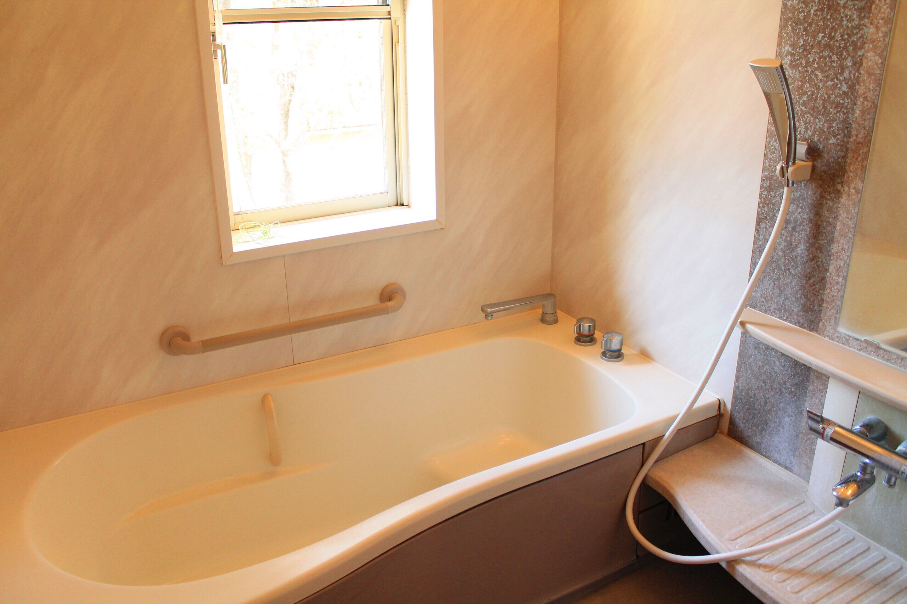 Une salle de bain avec une baignoire, une fenêtre et une douche.