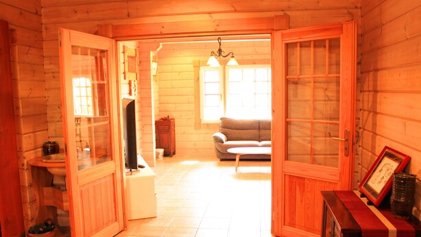 Interior d'una cabana de fusta amb un bany, una zona d'estar amb un sofà i una taula de menjador.