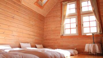 Una habitación acogedora tipo cabaña de madera con una cama, dos ventanas y una mesa con una lámpara.