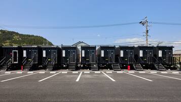 A row of portable cabins with numbered doors, steps, and a parking area.