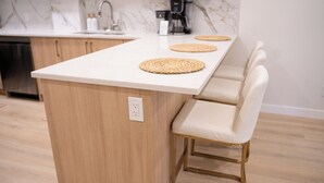 A modern kitchen with a white countertop, wooden cabinets, and a built-in coffee maker.