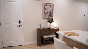 A modern, minimalist room with a wooden bench, a white table, and a framed artwork on the wall.
