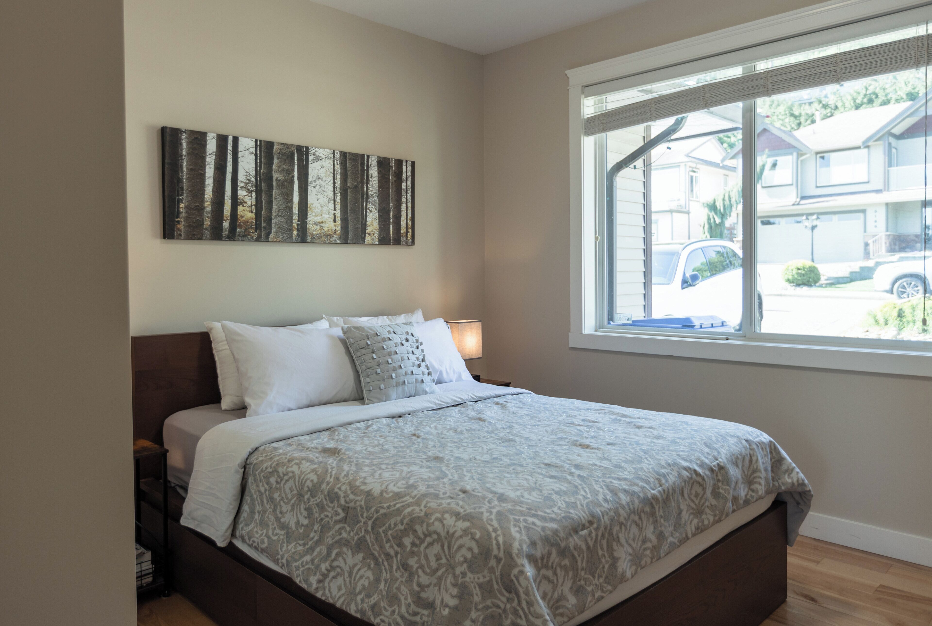 Ein Schlafzimmer mit Bett, Fenster und einem Wandbild.
