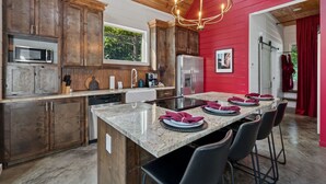 Una cucina moderna con mobili in legno, un piano di lavoro in granito e una parete di accento rosso.